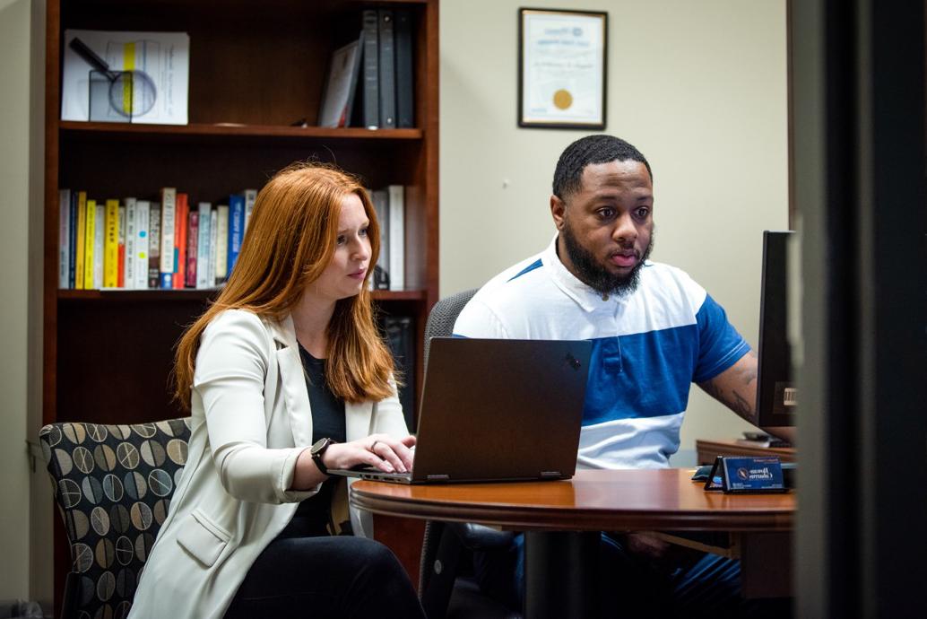 A man and woman sitting at an office, both using computers.